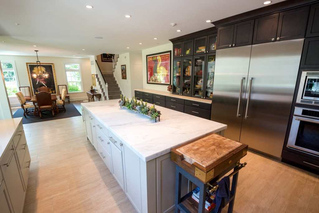Modern kitchen with marble island, dark cabinets, stainless steel appliances, and vibrant wall art, featuring an adjacent dining area.