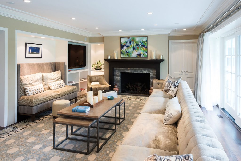 Cozy living room with plush sofas, a modern fireplace, and vibrant art. Natural light floods through large windows, highlighting elegant decor and a stylish coffee table.