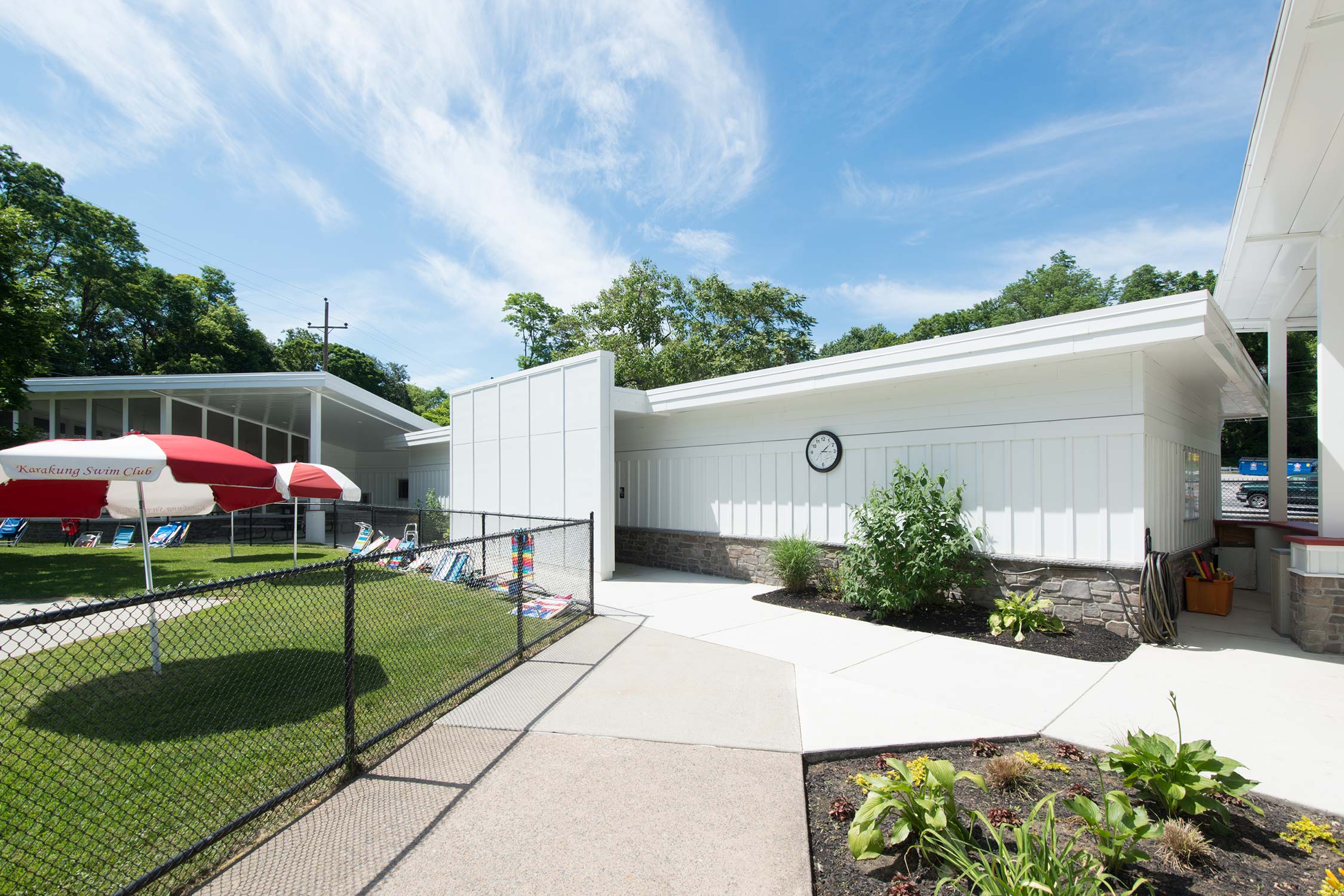 Karakung Swim Club in Ardmore, PA, with clubhouse, lawn, and red umbrellas.