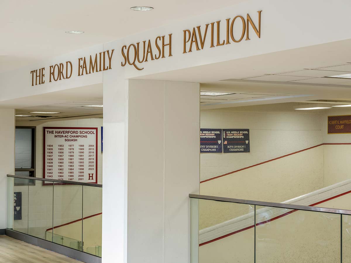 The Ford Family Squash Pavilion at The Haverford School with squash courts and glass walls. Walls display championship banners and an