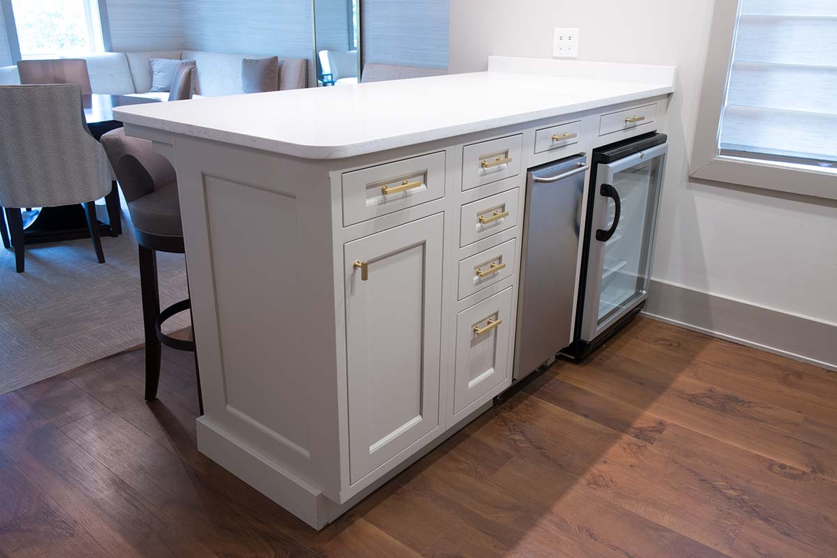 Modern kitchen island with white cabinets, mini fridge, dishwasher, and bar stools.