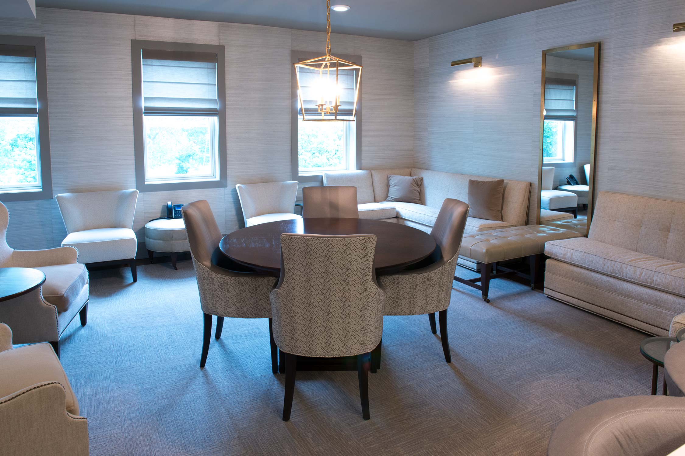 Elegant lounge with round table, chairs, sofa, chandelier, and large mirror.
