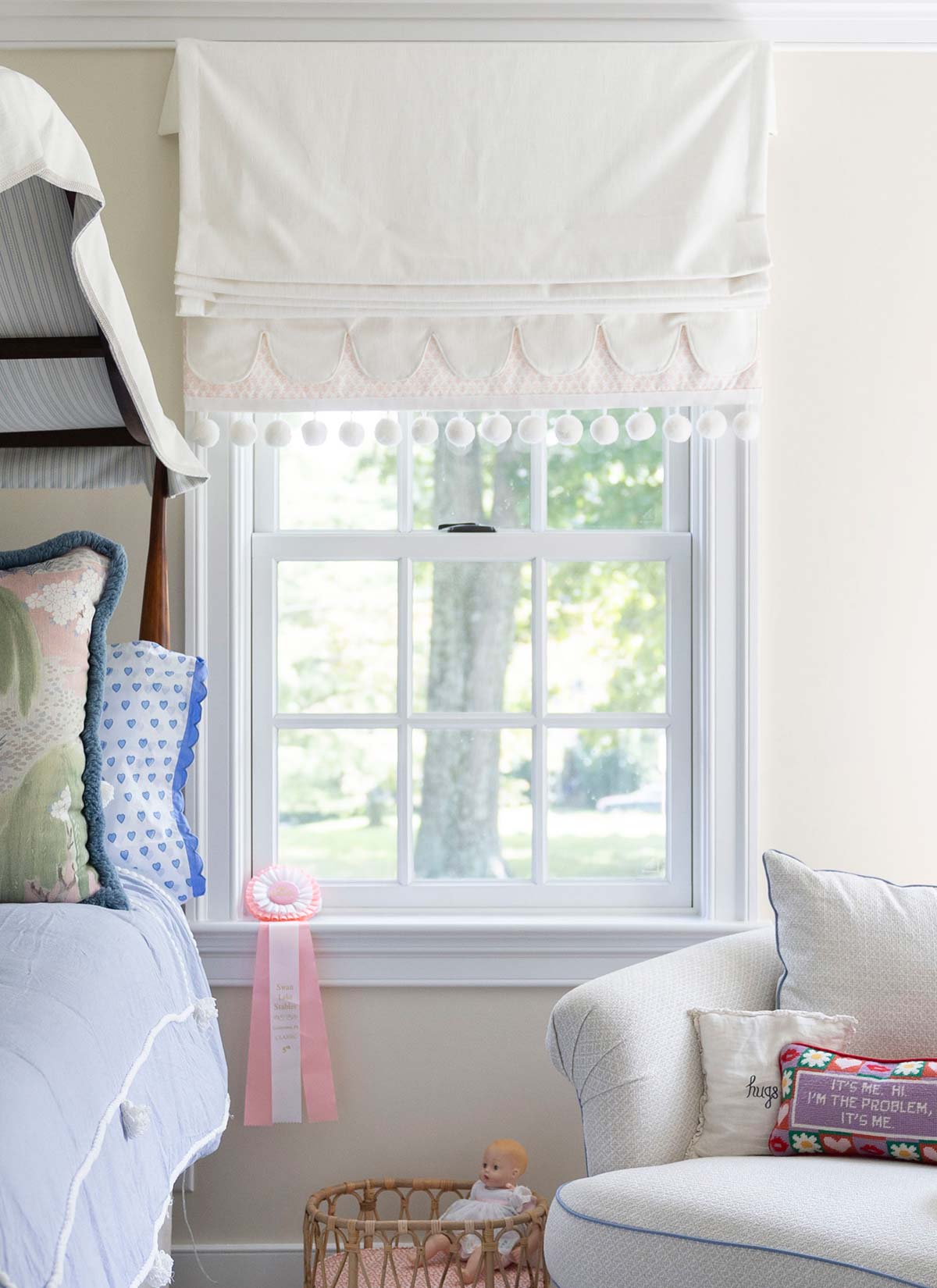 A charming child's room with a cozy bed, decorative curtains, a window with a ribbon, and a plush chair with a playful pillow.