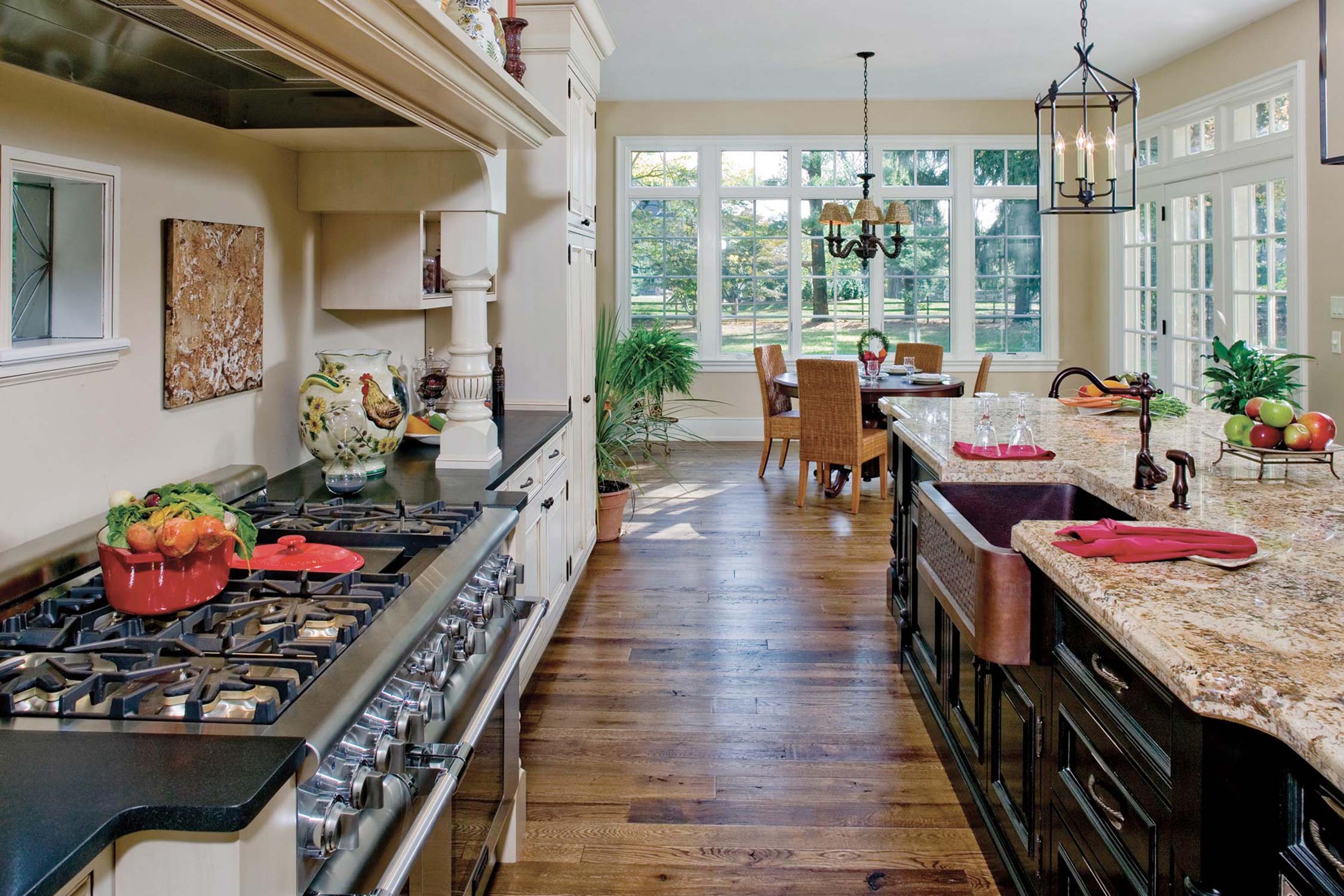 Spacious kitchen with modern stove, granite countertops, and a bright dining area with large windows and elegant lighting.