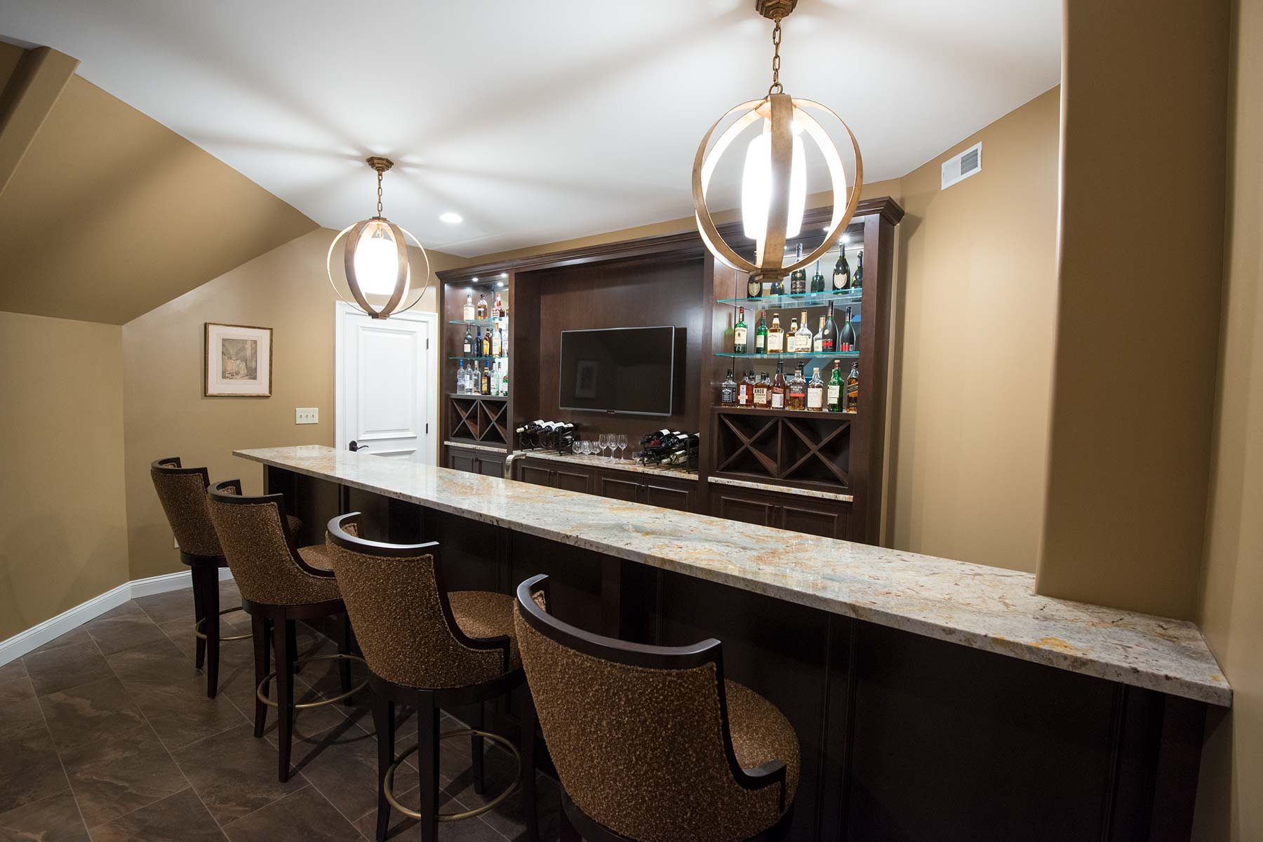 Stylish bar area with granite counter, elegant pendant lights, and a well-stocked wine and liquor display.