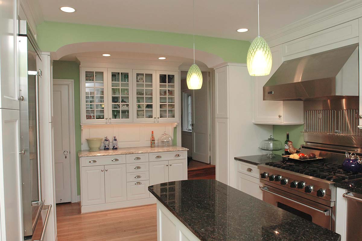 Bright kitchen with green ceiling, white cabinets, black granite counter, stainless steel appliances, and hardwood floors under soft lights.