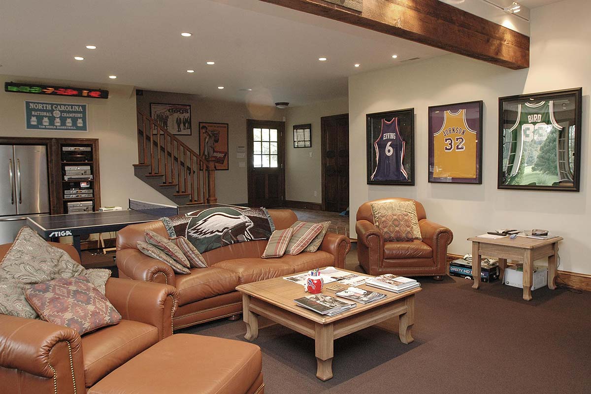 Cozy living room with leather furniture, ping pong table, and framed sports jerseys, featuring a warm ambiance.