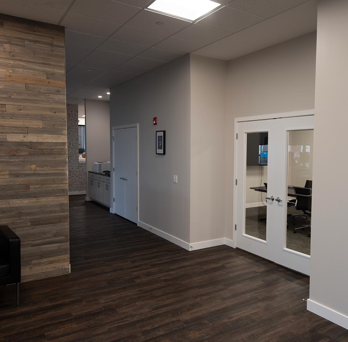Modern office hallway at the Swisco headquarters with wooden floor, and a glass conference room.