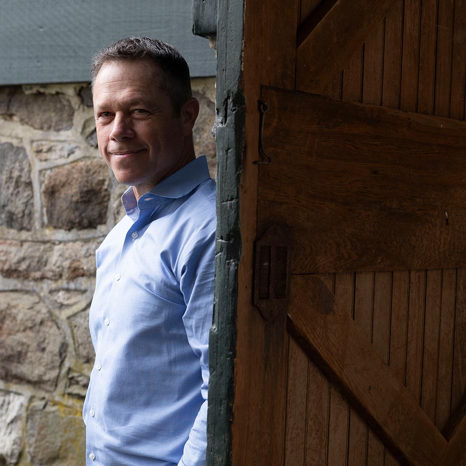 Andy Kerns, Ranieri & Kerns founder, stands before a rustic wooden door and stone-facade home.