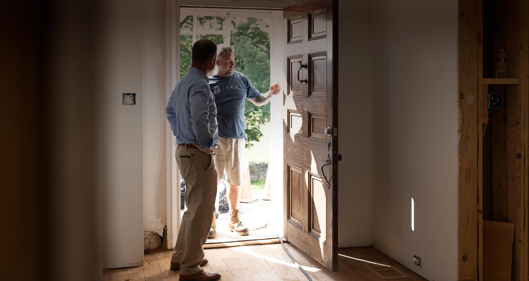 Andy Kerns and a Ranieri & Kerns superintendent talking at an open wooden door in a home under construction.