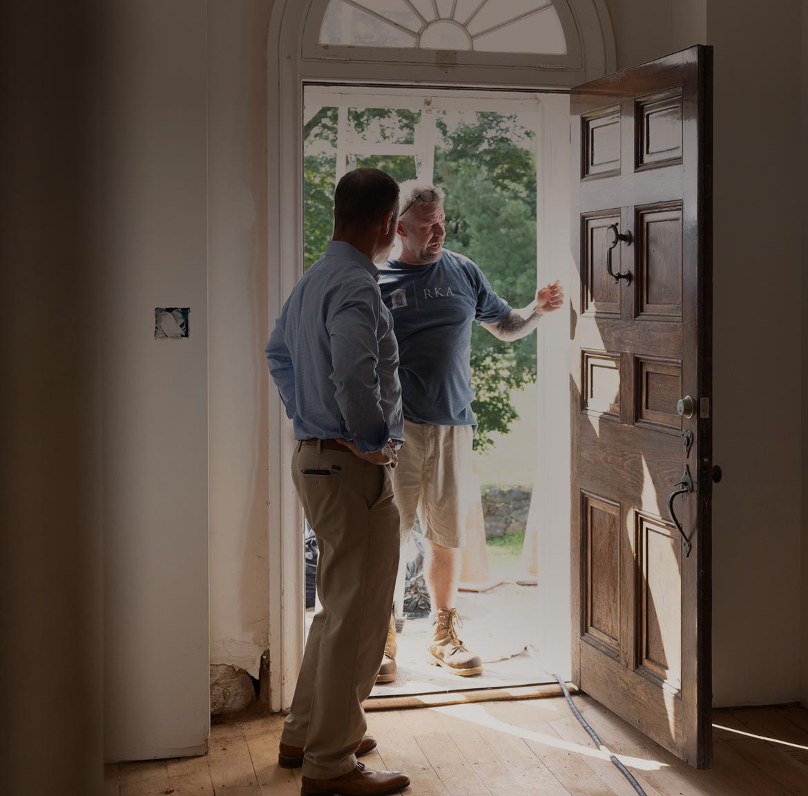Andy Kerns and a Ranieri & Kerns superintendent talking at an open wooden door in a home under construction.
